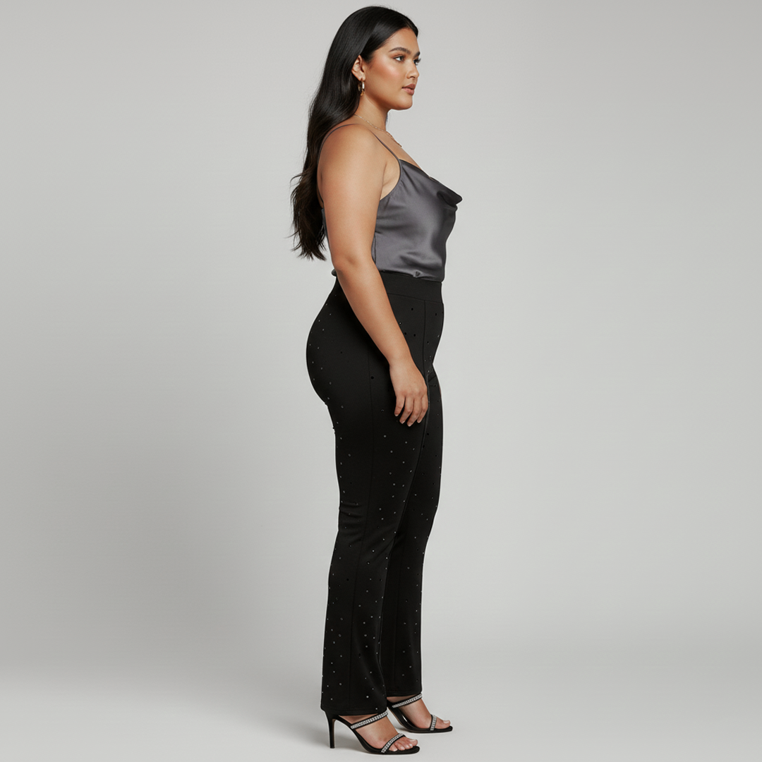 Woman wearing a silver top and black pants on a plain background