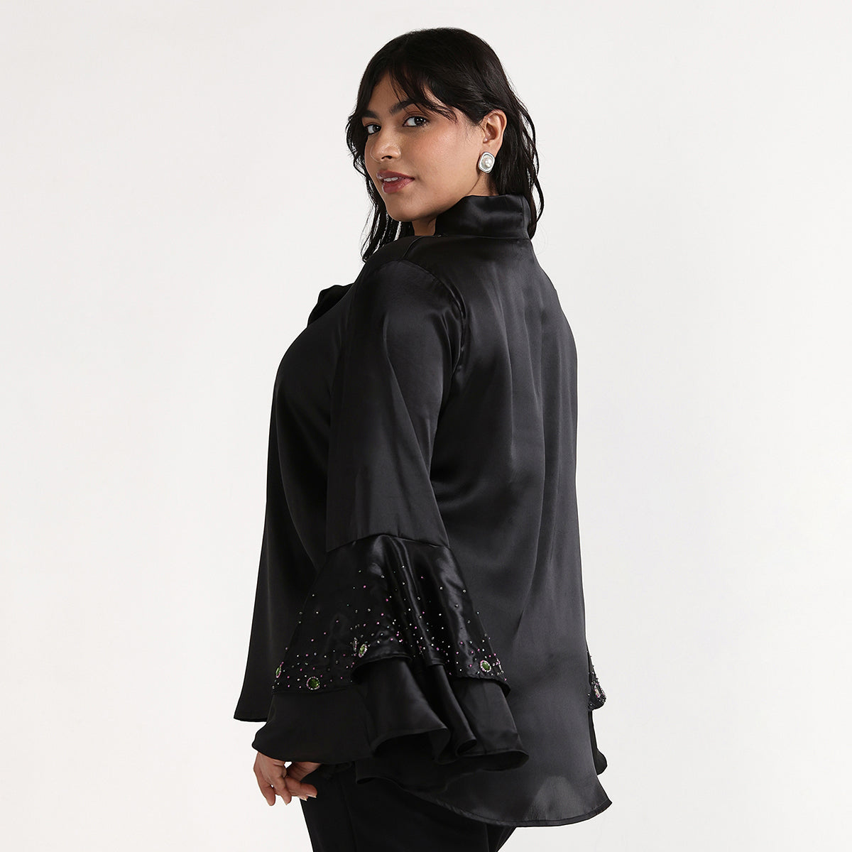 Woman wearing a black blouse with embellished cuffs on a white background