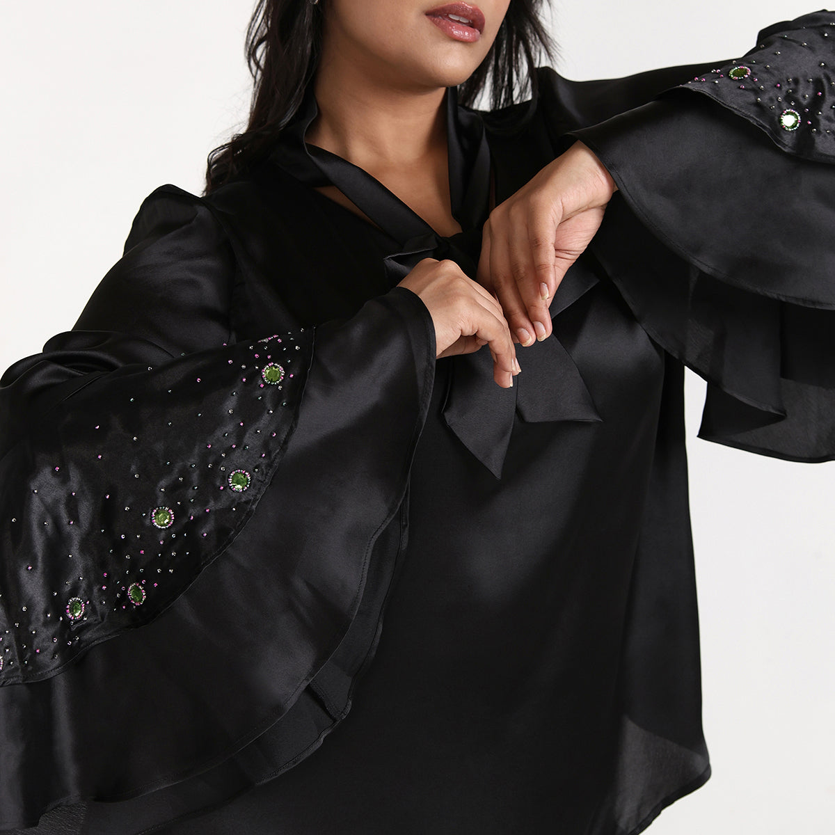 Black satin garment with embellishments on a plain background