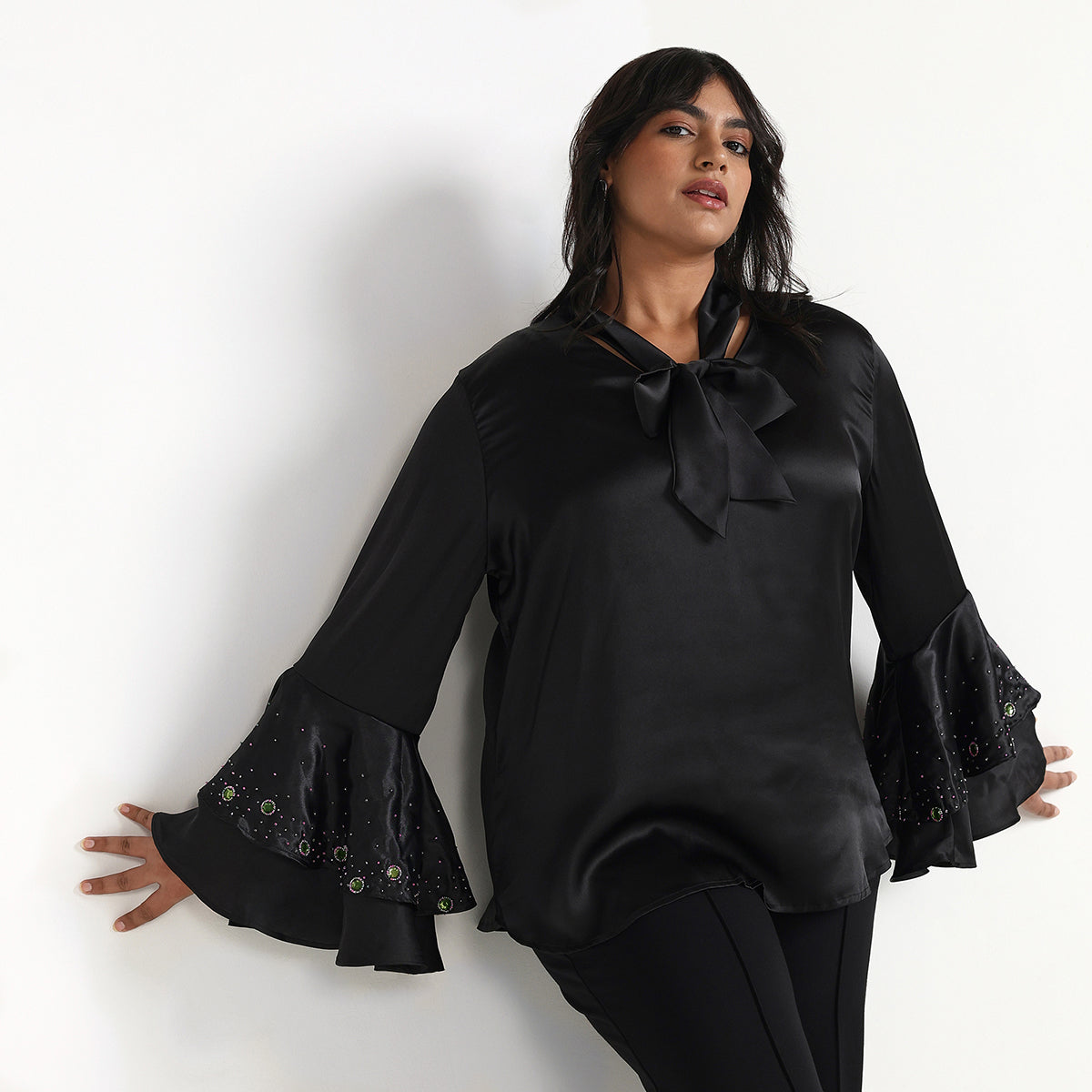 Woman wearing a black blouse with ruffled sleeves against a white background