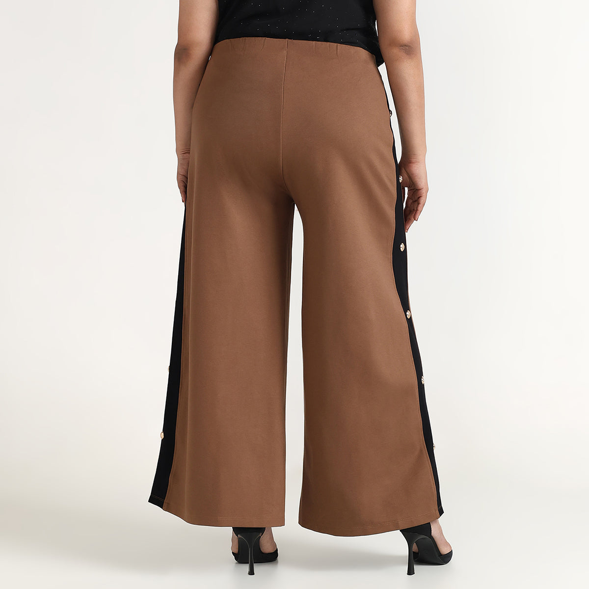 Brown wide-leg pants with black side panels worn by a person on a white background