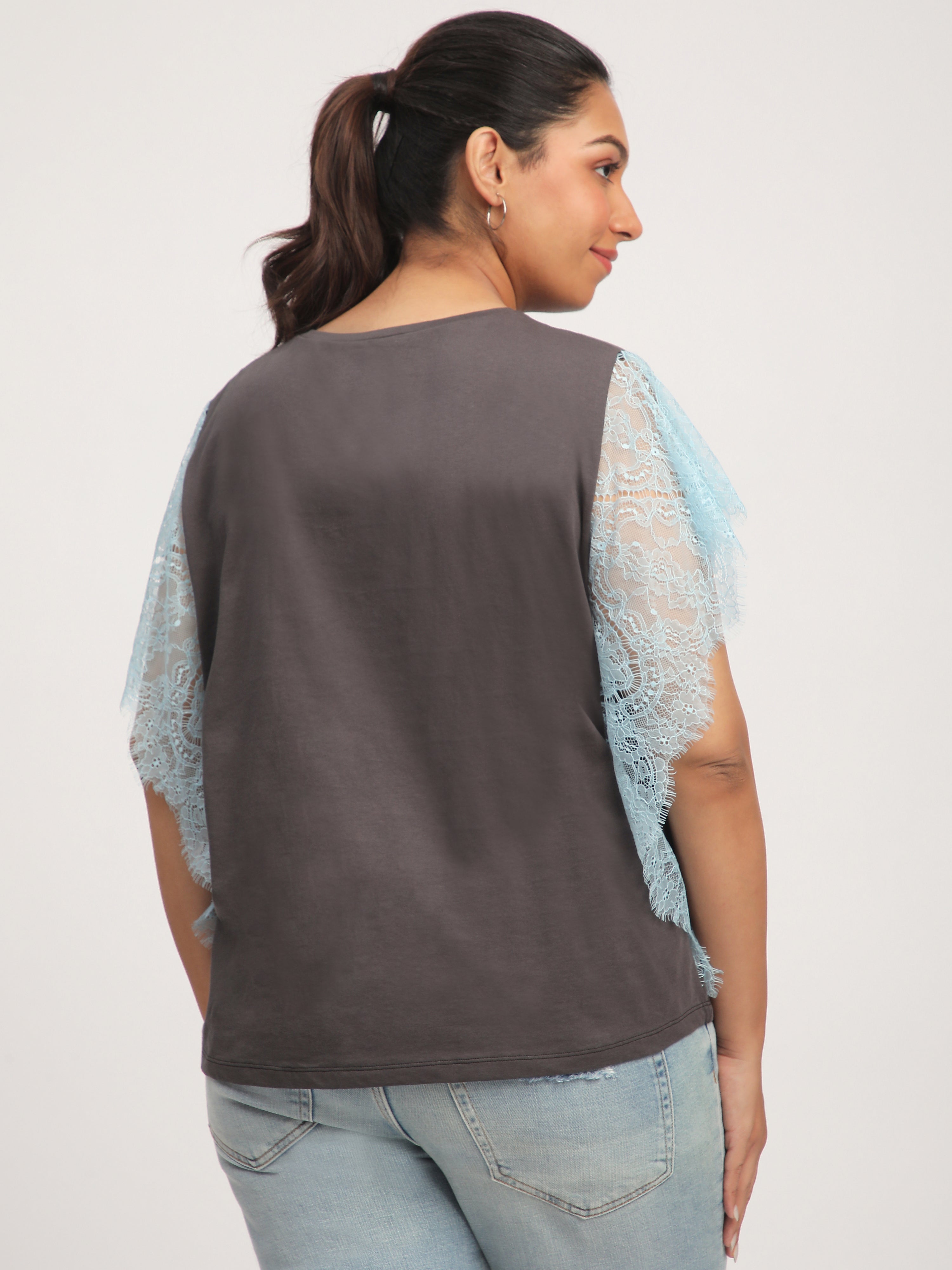 Woman wearing a dark brown top with light blue lace sleeves.