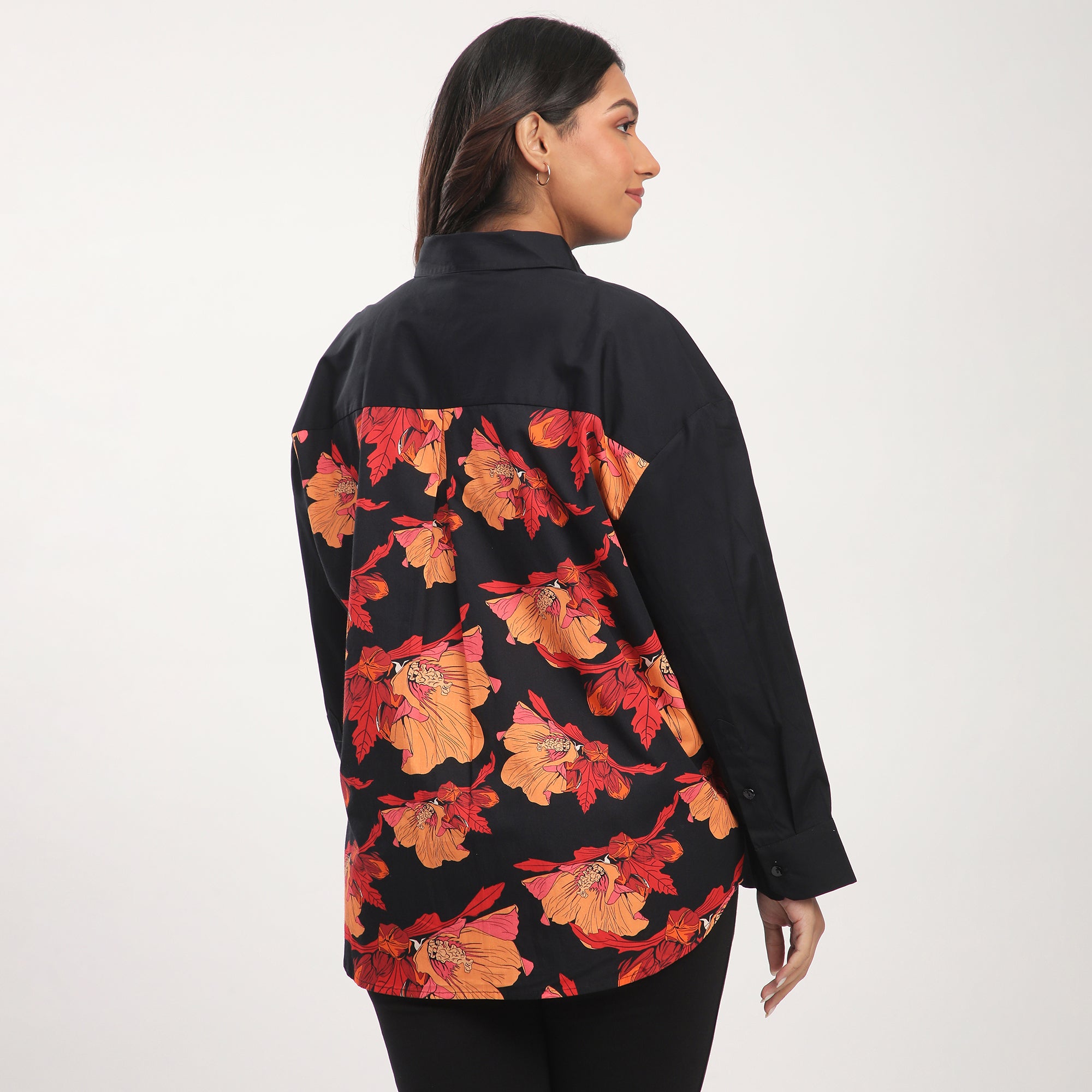 Woman wearing a black shirt with red and orange floral pattern on a white background