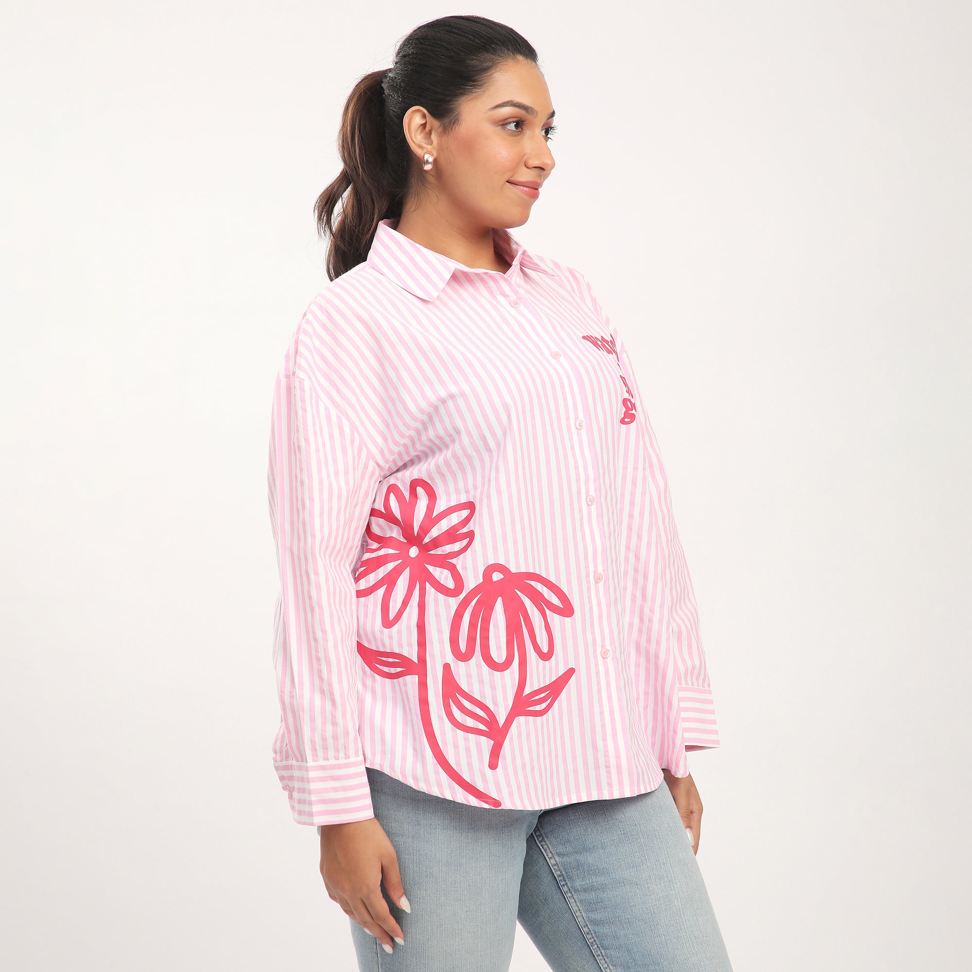 Woman wearing a pink and white striped shirt with floral designs on a white background