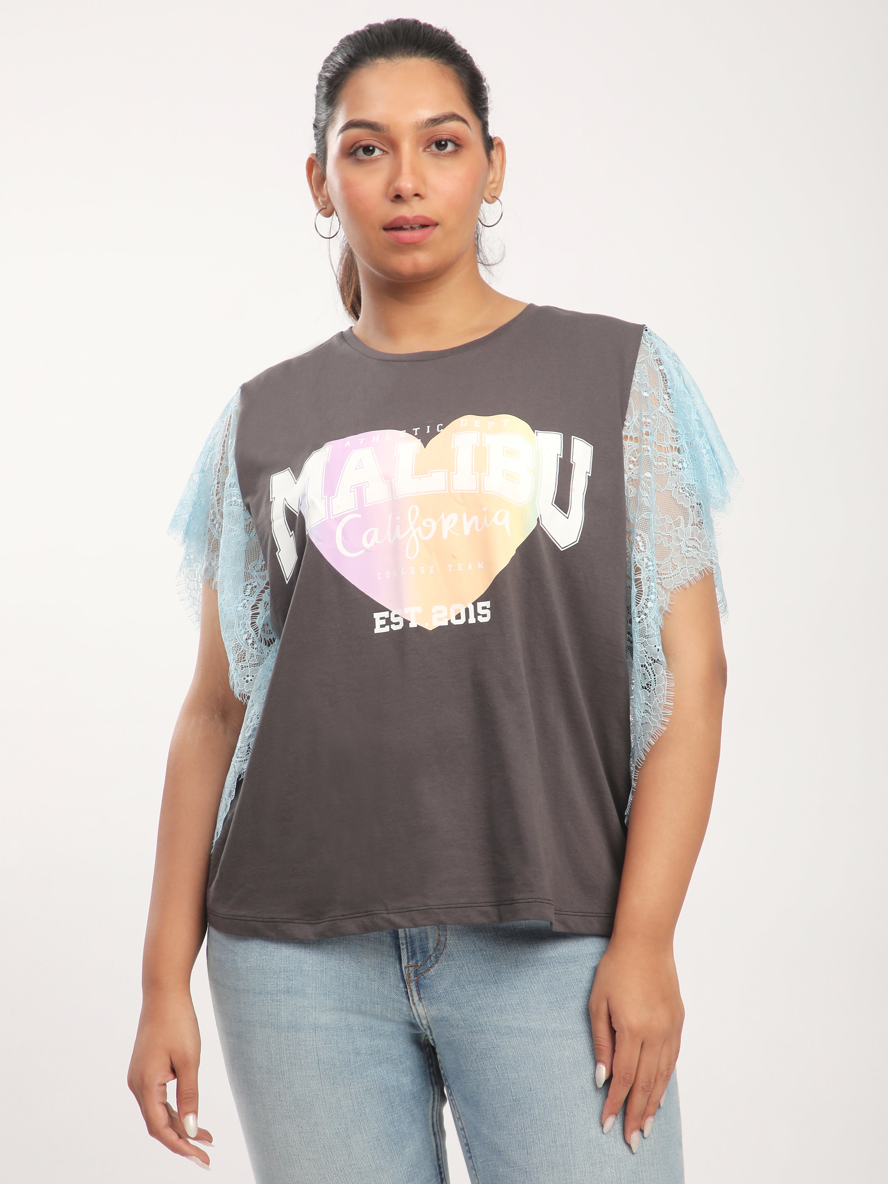 Woman wearing a dark gray t-shirt with colorful heart design and text.