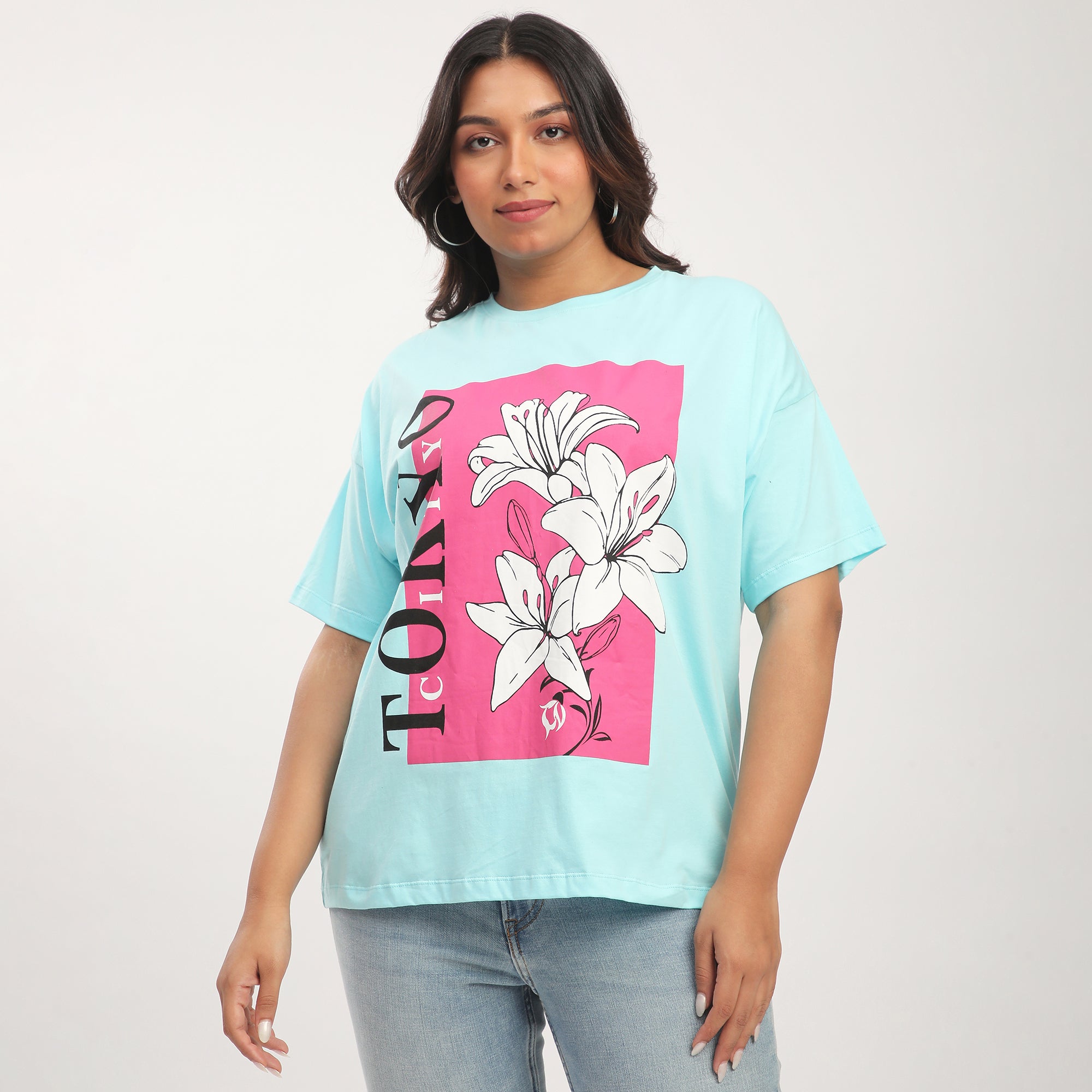 A woman wearing a plus size turquoise cotton floral printed drop shoulder t-shirt with the text 'Tokyo' on it.