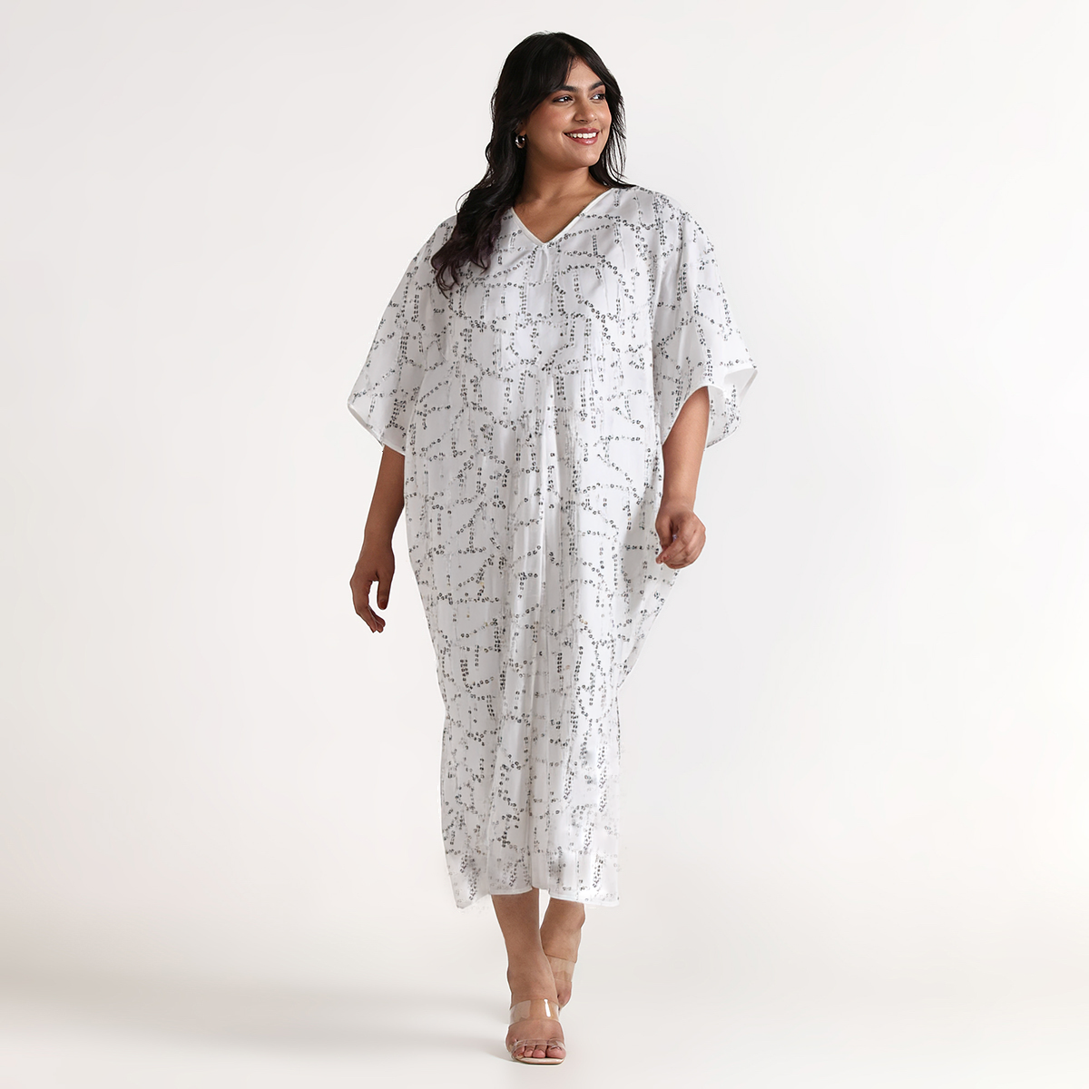 Woman wearing a white kaftan patterned dress on a white background