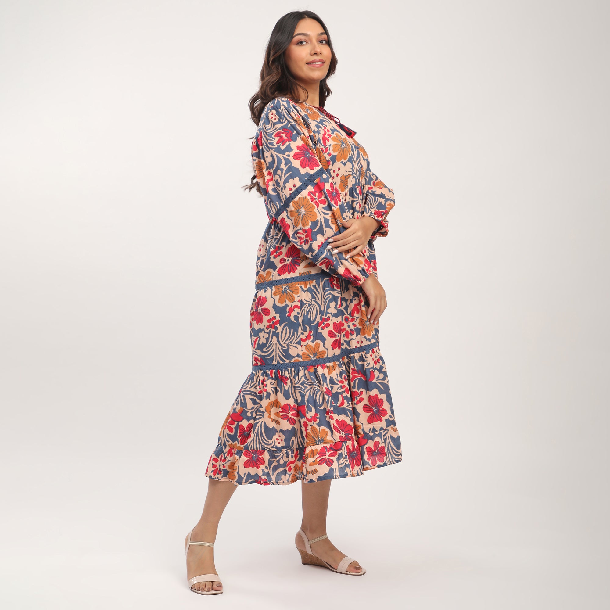 A model wearing a plus size blue cotton floral printed maxi dress with lace inserts, standing against a white background.