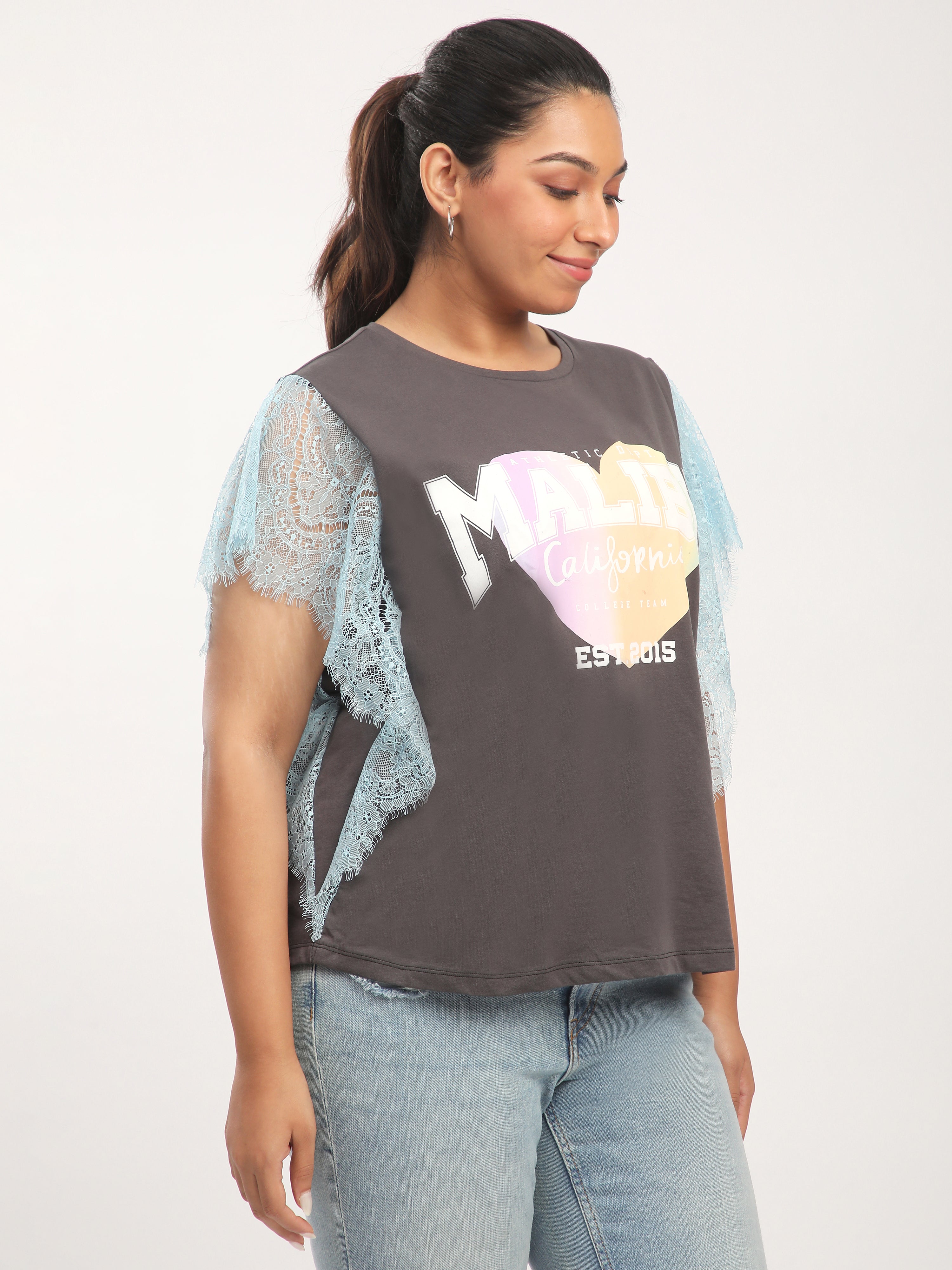 Woman wearing a graphic t-shirt with colorful design and ripped sleeves.