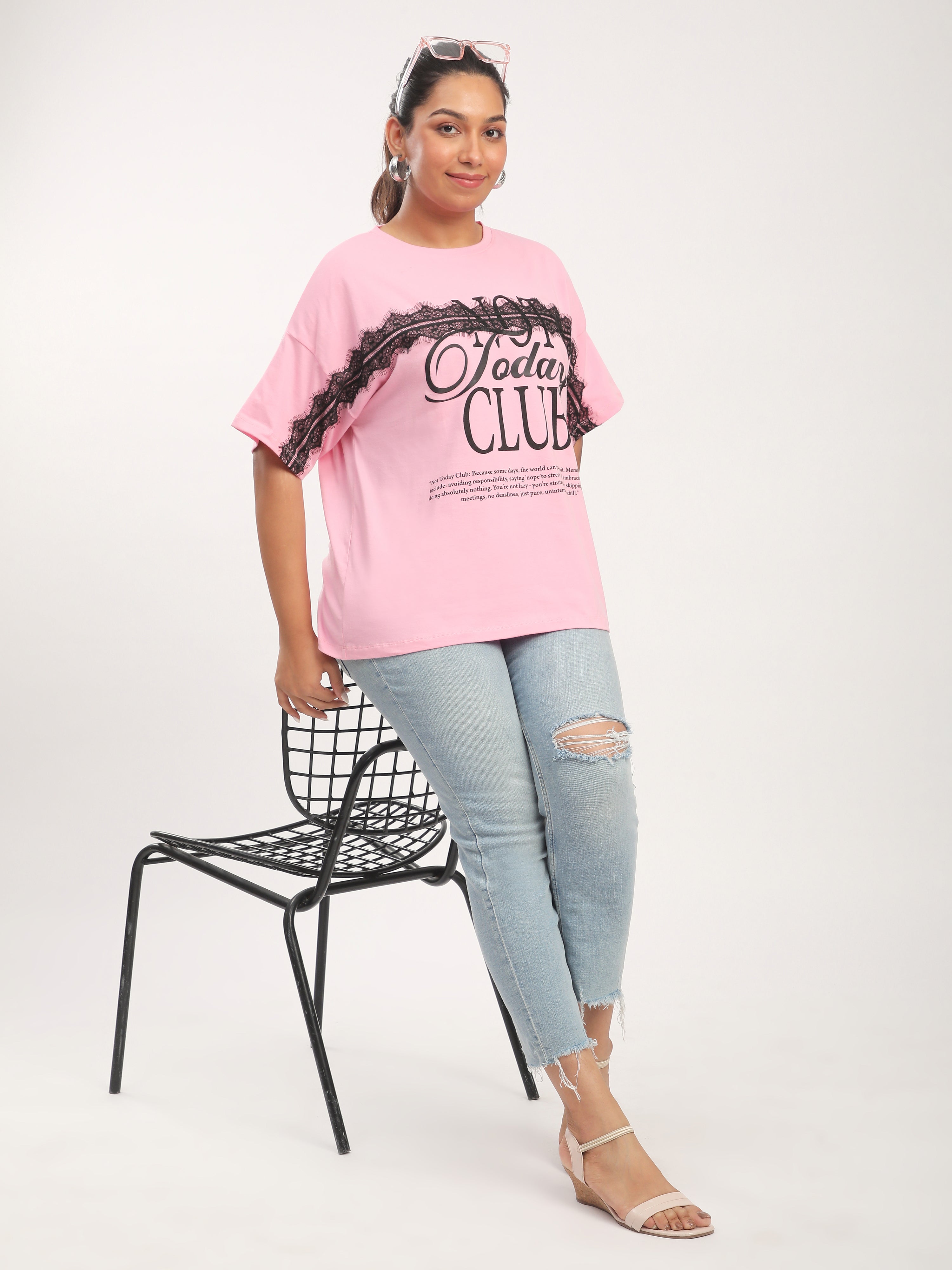 Woman in pink t-shirt and jeans standing next to a chair on a white background