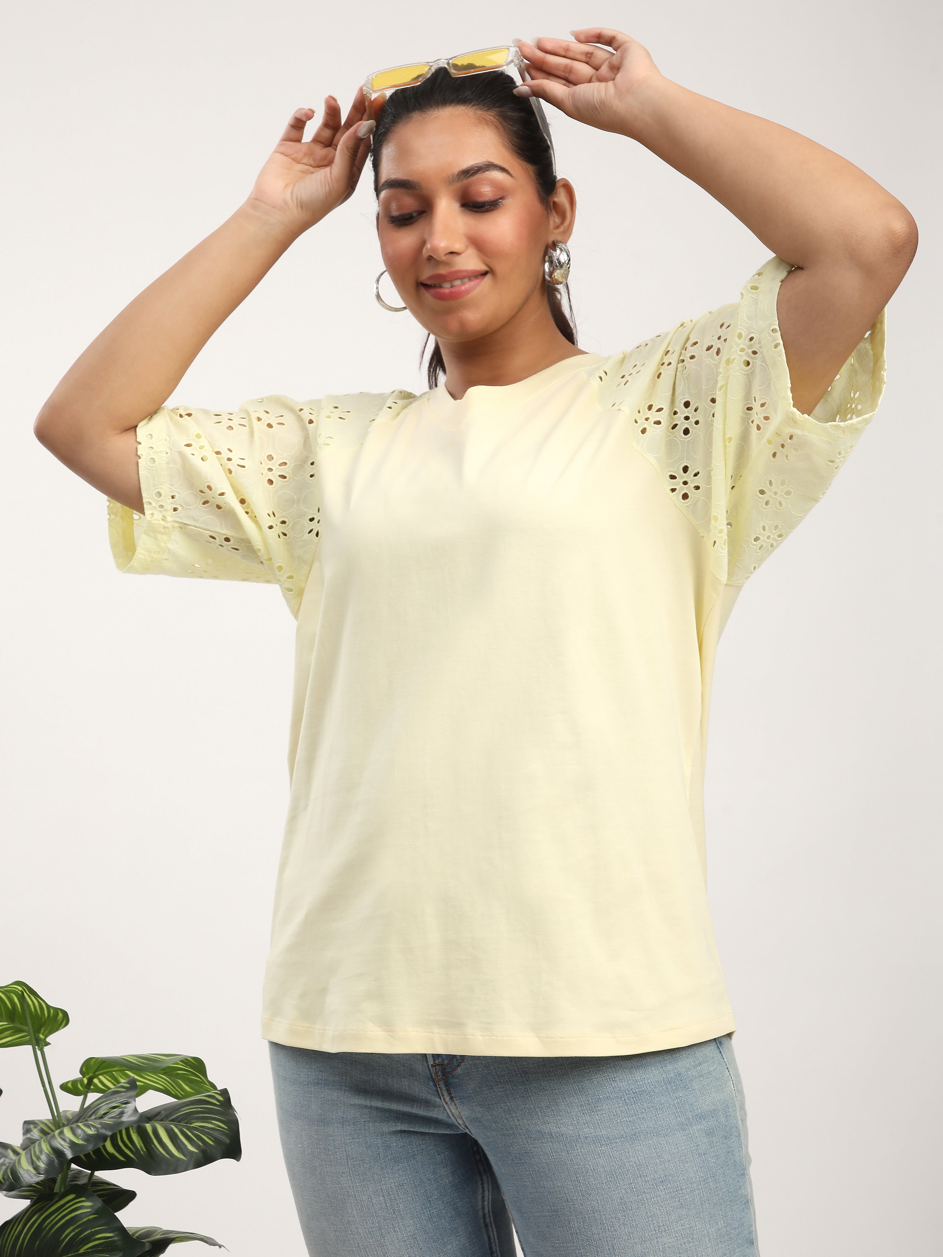 A model wearing a light yellow cotton jersey top with embroidered raglan sleeves, paired with blue jeans.