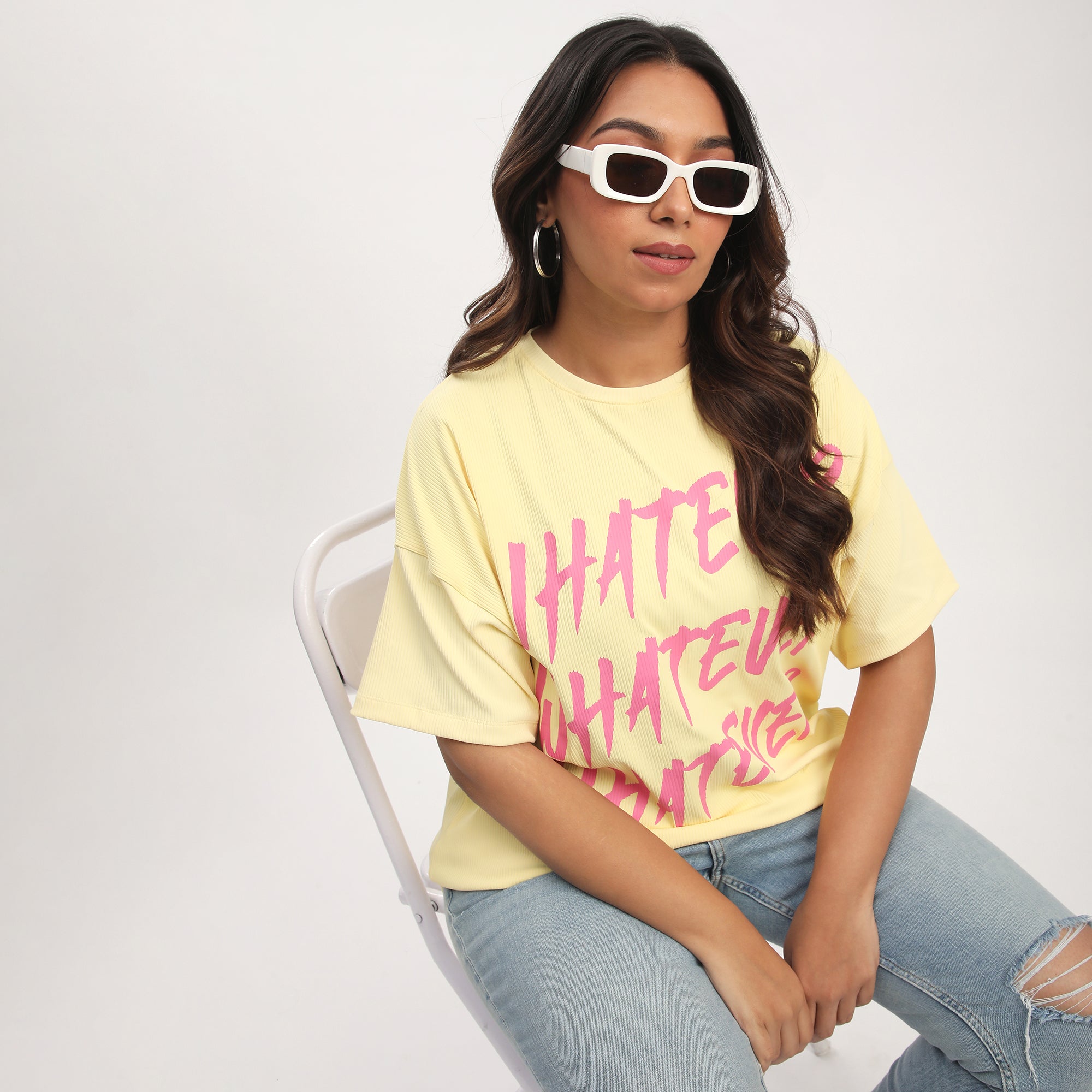 Person sitting on a chair wearing a yellow t-shirt with pink text.