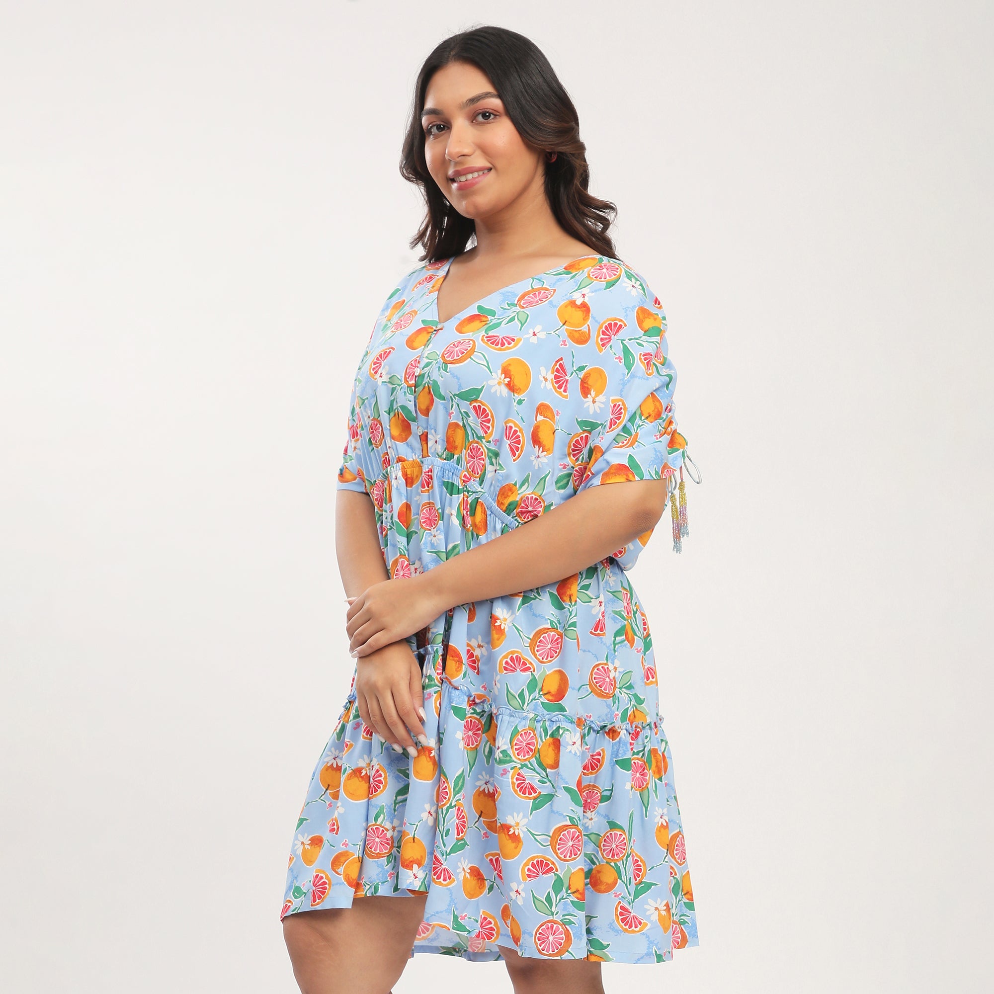 Woman wearing a blue floral dress with fruit patterns on a white background